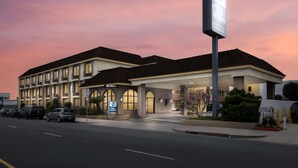 Een hotel met een 'Best Western' bord, meerdere balkons en een parkeerplaats.