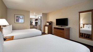 Een hotelkamer met twee bedden, een televisie, een bureau en een spiegel.