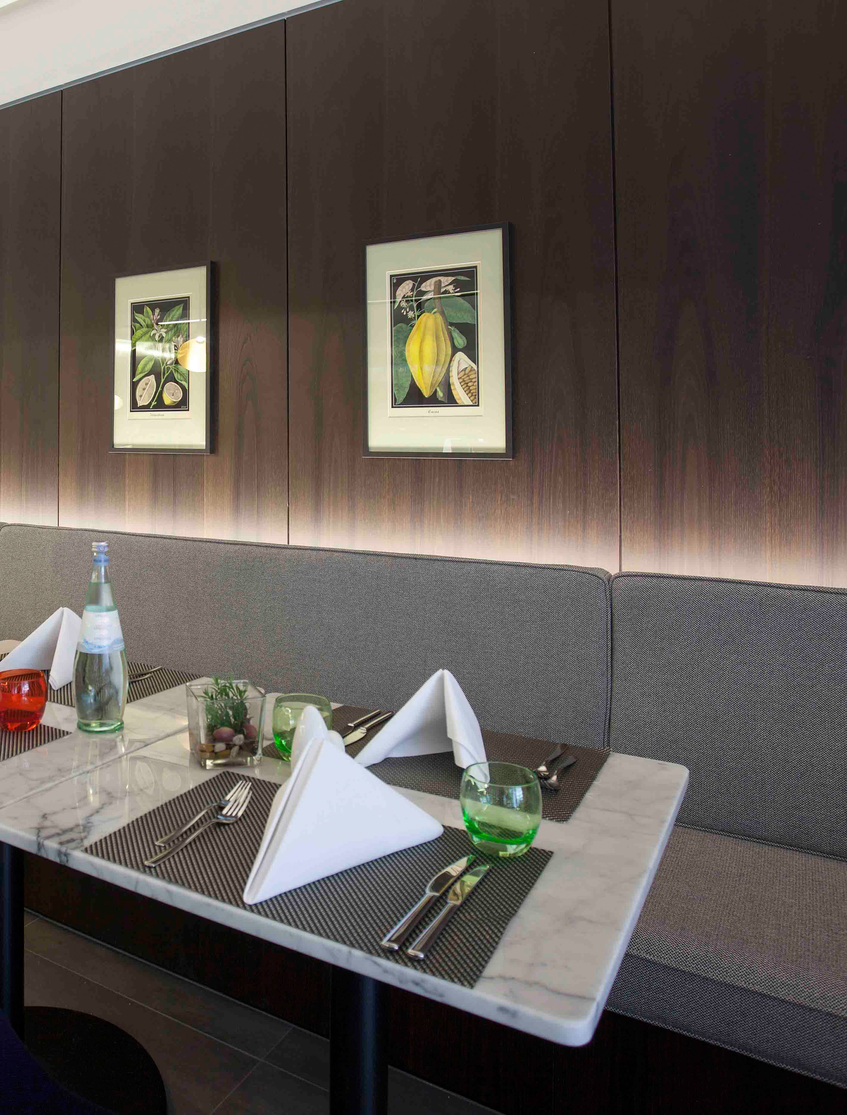 Comedor con una mesa lista para dos personas, que incluye una botella de agua, un vaso con una bebida verde y una planta pequeña.