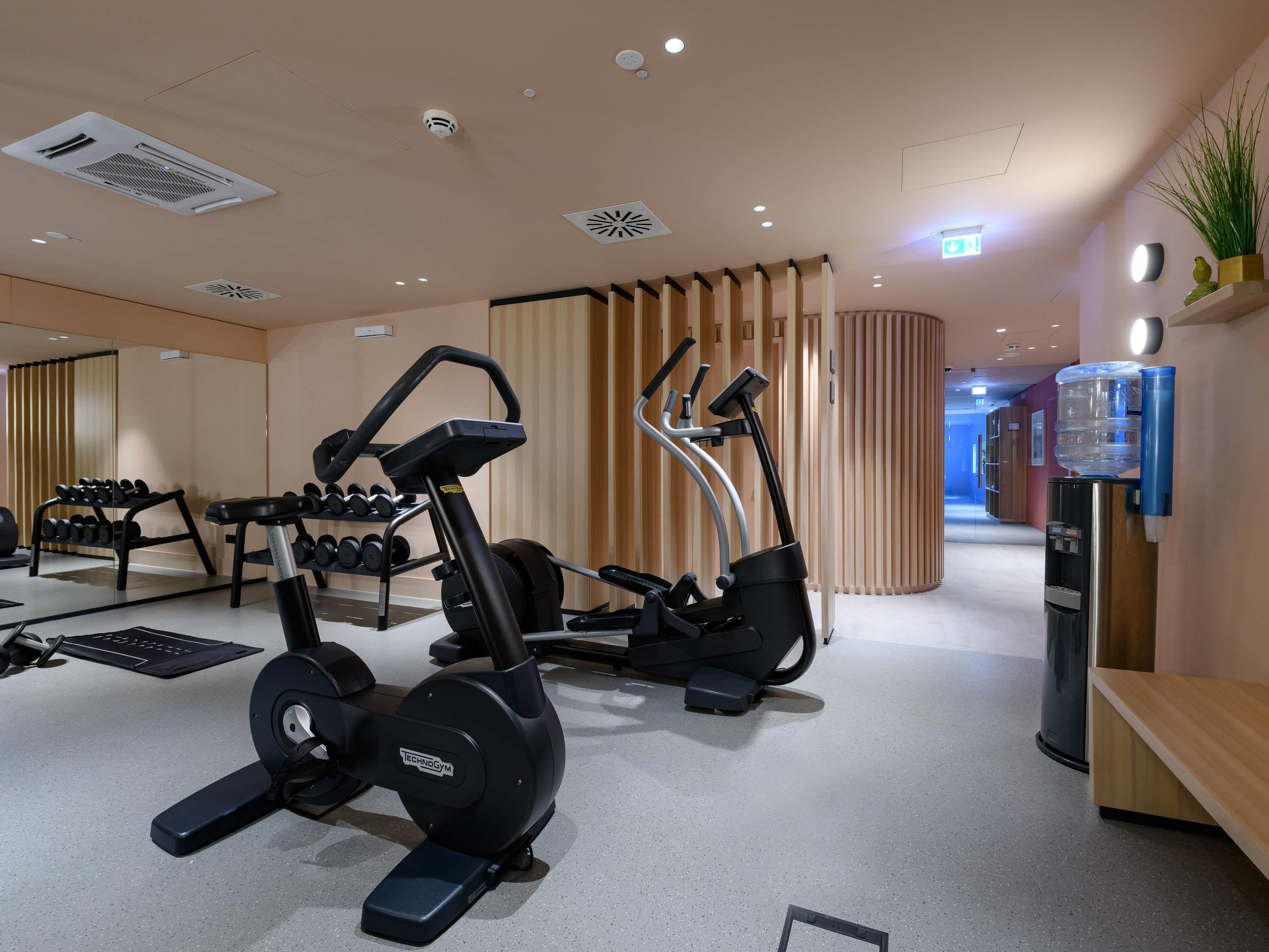 A gym with exercise equipment, a water dispenser, and a mirror.