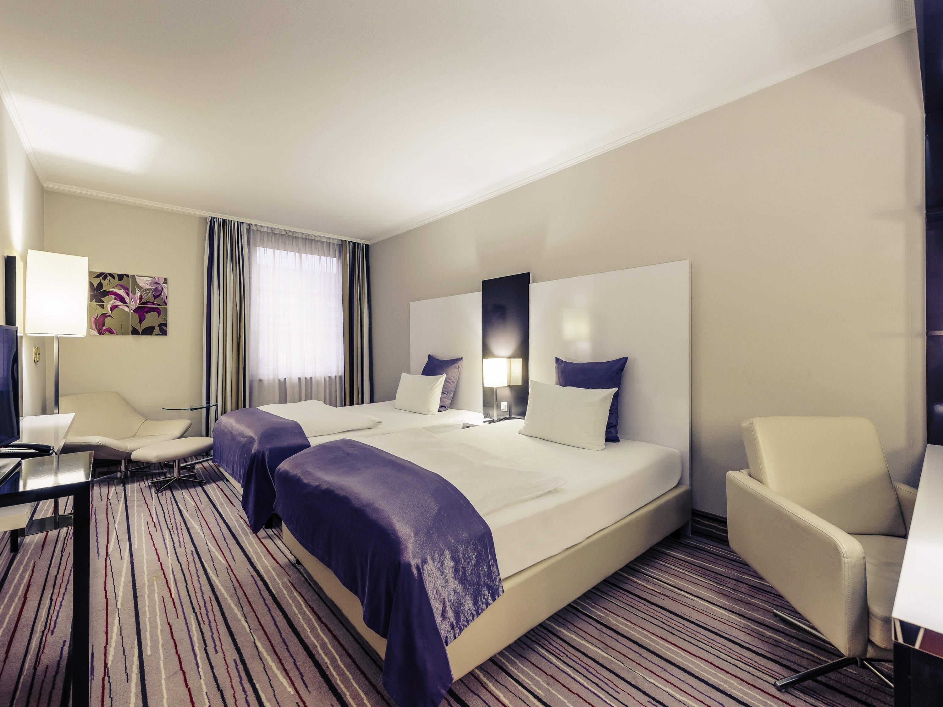 Ein Hotelzimmer mit einem großen Bett, zwei Nachttischen, einem Schreibtisch und einem Stuhl.