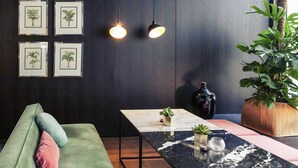 Un interior moderno con un sofá verde, una mesa de mármol e impresiones botánicas enmarcadas en la pared.