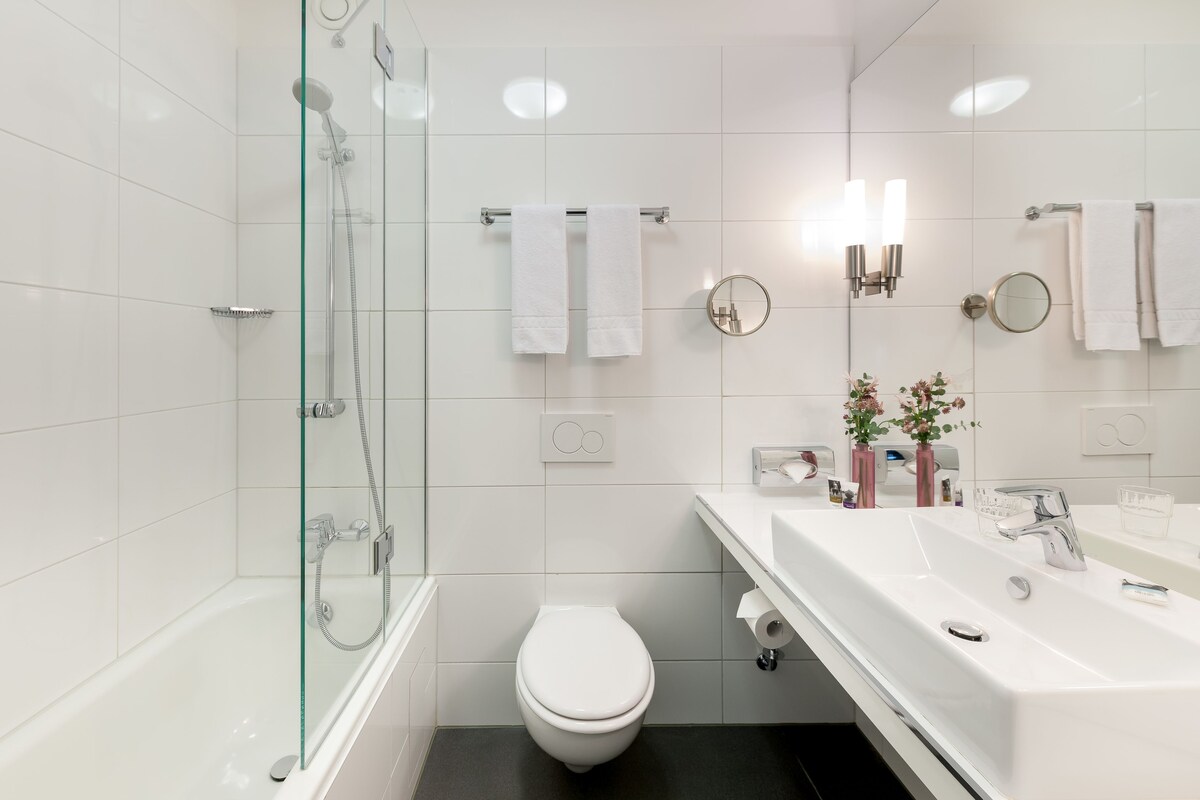 A modern bathroom with a glass-enclosed shower, a white toilet, and a vanity with a sink and mirror.