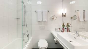 A modern bathroom with a glass-enclosed shower, a white toilet, and a vanity with a sink and mirror.