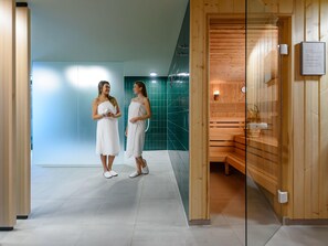 A modern spa area with a wooden sauna and a glass-walled steam room.