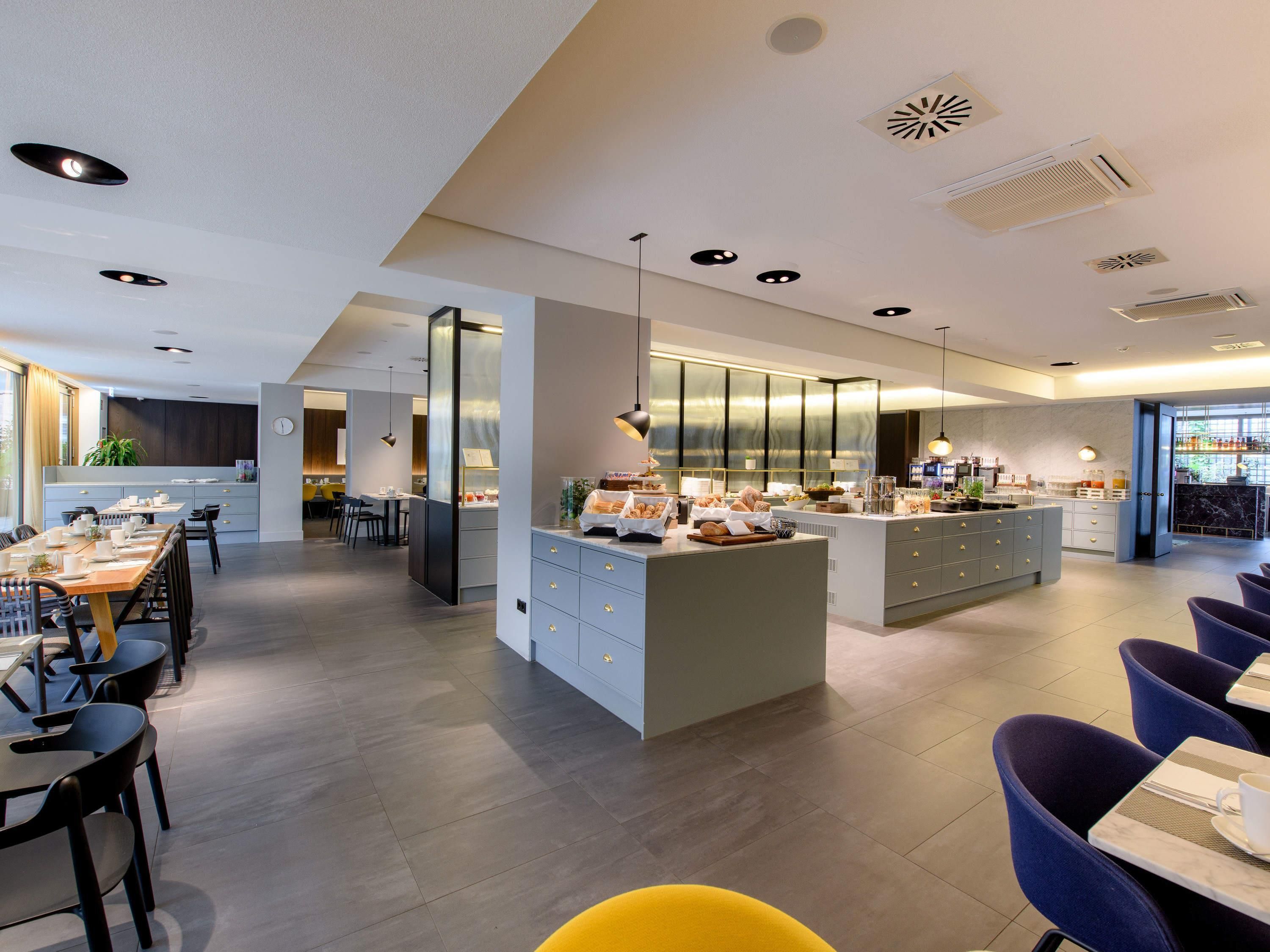 Una cocina moderna con una isla central, comedor con sillas y una zona de bar con asientos.