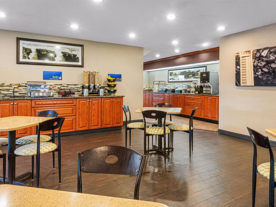 Een restaurantgedeelte in een hotel, met houten kasten, een buffet en een zithoek met tafels en stoelen.