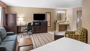 A hotel room with a bed, a desk with a computer, a TV, a chair, a sofa, and a bathroom with a mirror and sink. - Best Western Providence Warwick Airport Inn (Warwick)