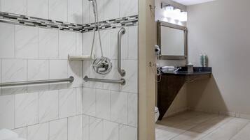 A modern bathroom with a shower, grab bars, a vanity with a mirror, and toiletries.