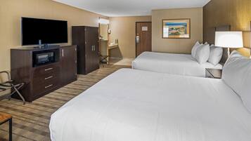 A hotel room with two beds, a TV, a microwave, a desk, and a painting on the wall.