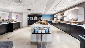 Een moderne hotel eetruimte met buffetten, een centrale bedieningsbalie en een zithoek.