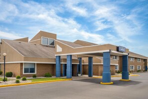 A modern hotel with a covered entrance, multiple windows, and a clear sky.