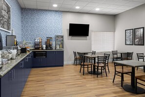 A modern kitchen with blue cabinets, a granite countertop, and a dining area with wooden chairs and tables.