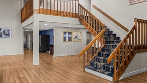 A spacious interior with a wooden staircase, a chandelier, and an American flag.