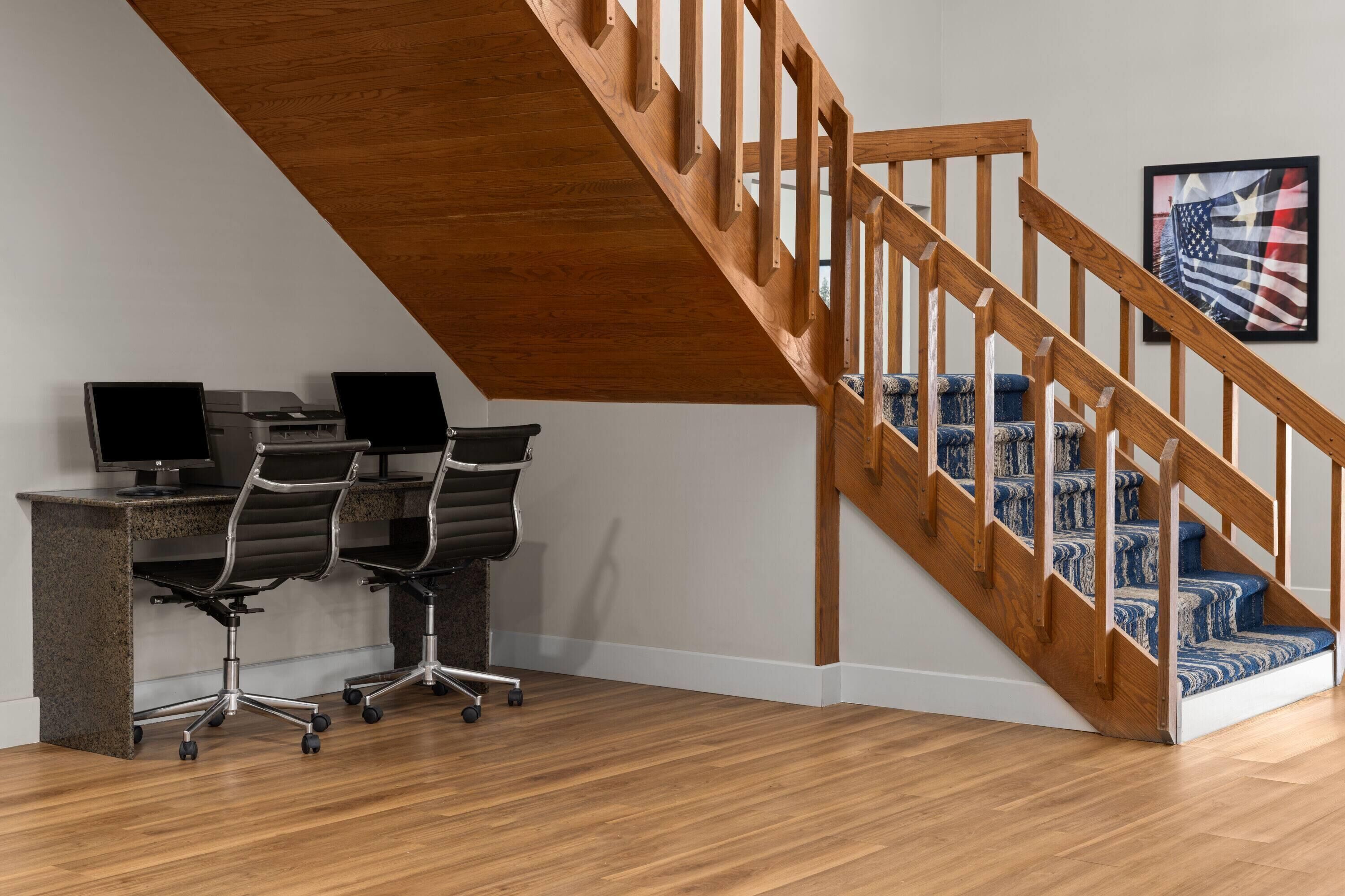 Een werkkamer met een bureau, twee stoelen en een computerinrichting.