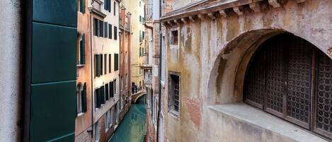 A narrow Venetian canal flanked by historic buildings with arched windows and balconies.
