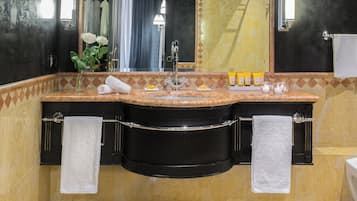 A bathroom with a black vanity, two sinks, a mirror, a towel rack, and toiletries.