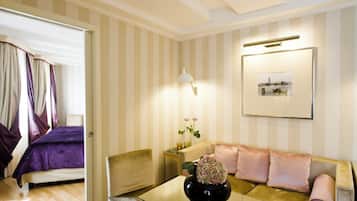 A hotel room with a bed, a sofa, a coffee table with a vase, and a wall-mounted lamp.