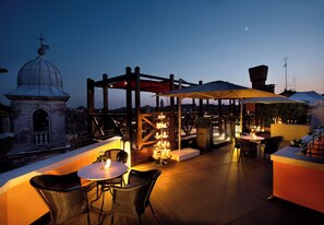An outdoor terrace with tables and chairs, a wooden pergola, and a view of a historic building with a dome. - Splendid Venice – Starhotels Collezione (Venice)