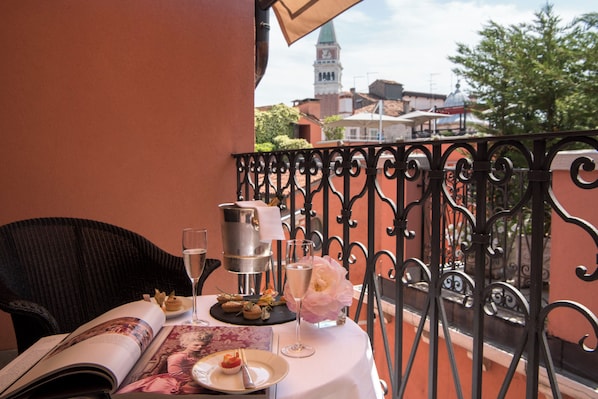 A table set with a menu, a bottle, a glass of water, and a flower on a balcony with a wrought iron railing. - Splendid Venice – Starhotels Collezione (Venice)