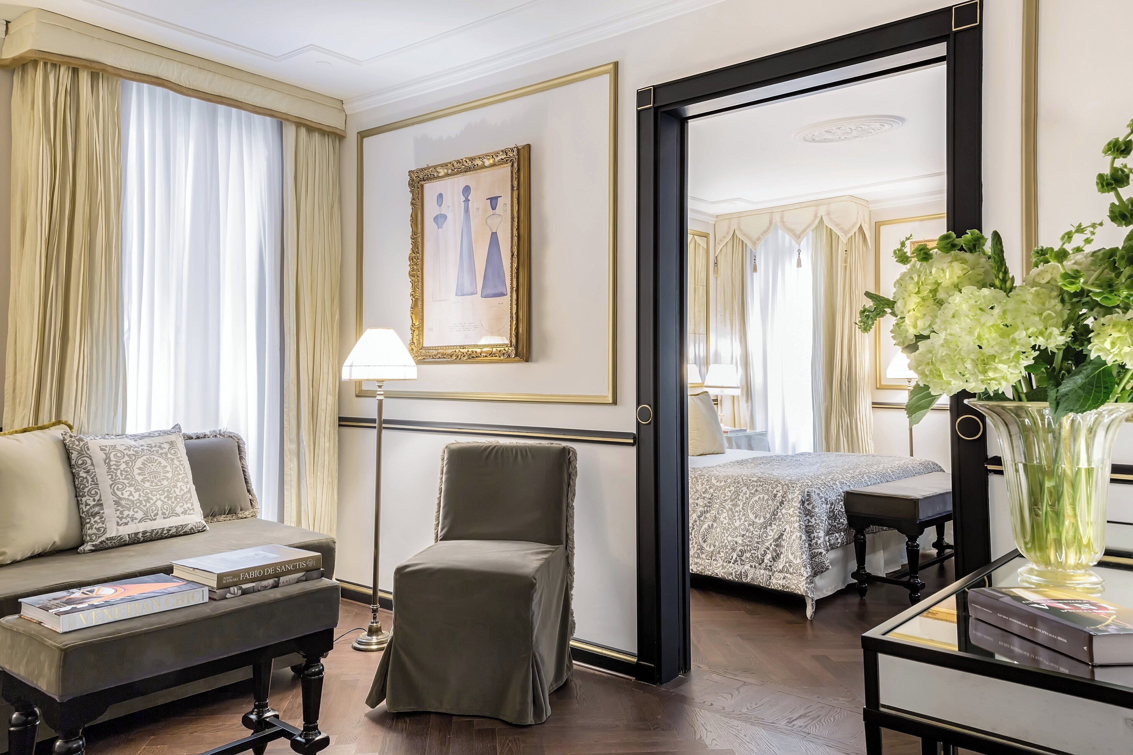 Et hotelværelse med sofa, lænestol, natbord og et stort spejl.