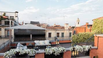 Una terrazza sul tetto con posti a sedere all'aperto, vista sulla città e un campanile sullo sfondo.