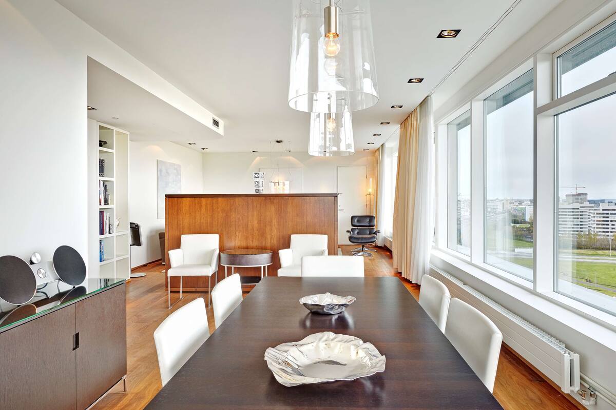 A modern conference room with a large table, white chairs, and a wooden panel wall.