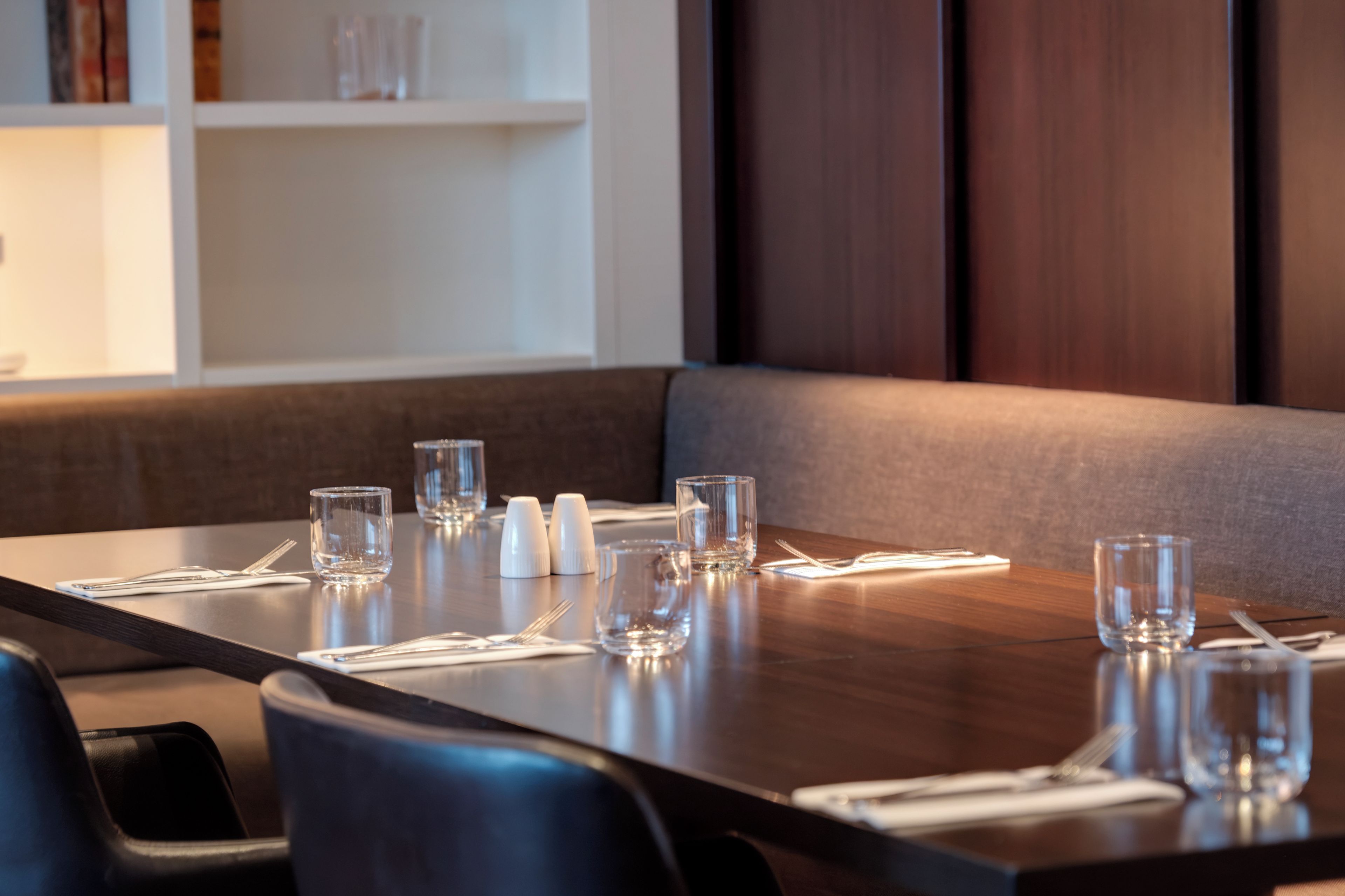 A dining table set with glasses, cutlery, and napkins.