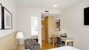 A hotel room with a bed, a desk, a chair, a lamp, and a picture on the wall. - Hilton Reykjavik (Reykjavik)