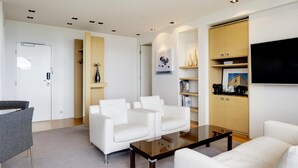 A modern living room with white sofas, a coffee table, and built-in shelving with books and decorative items. - Hilton Reykjavik Nordica (Reykjavik)