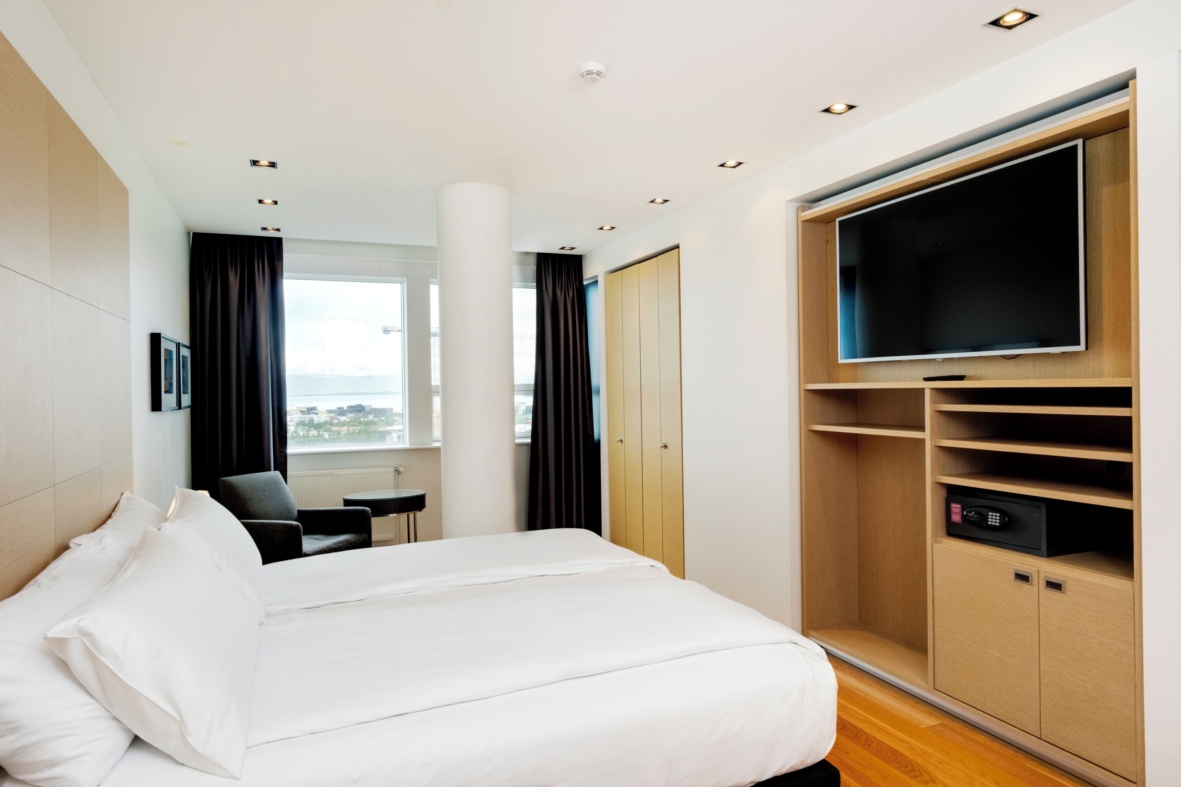 Ein Hotelzimmer mit einem Bett, einem Schreibtisch, einem Fernseher und einem Kleiderschrank.