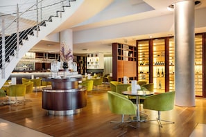 A modern interior with a central bar area, seating, and a staircase. - Hilton Reykjavik (Reykjavik)