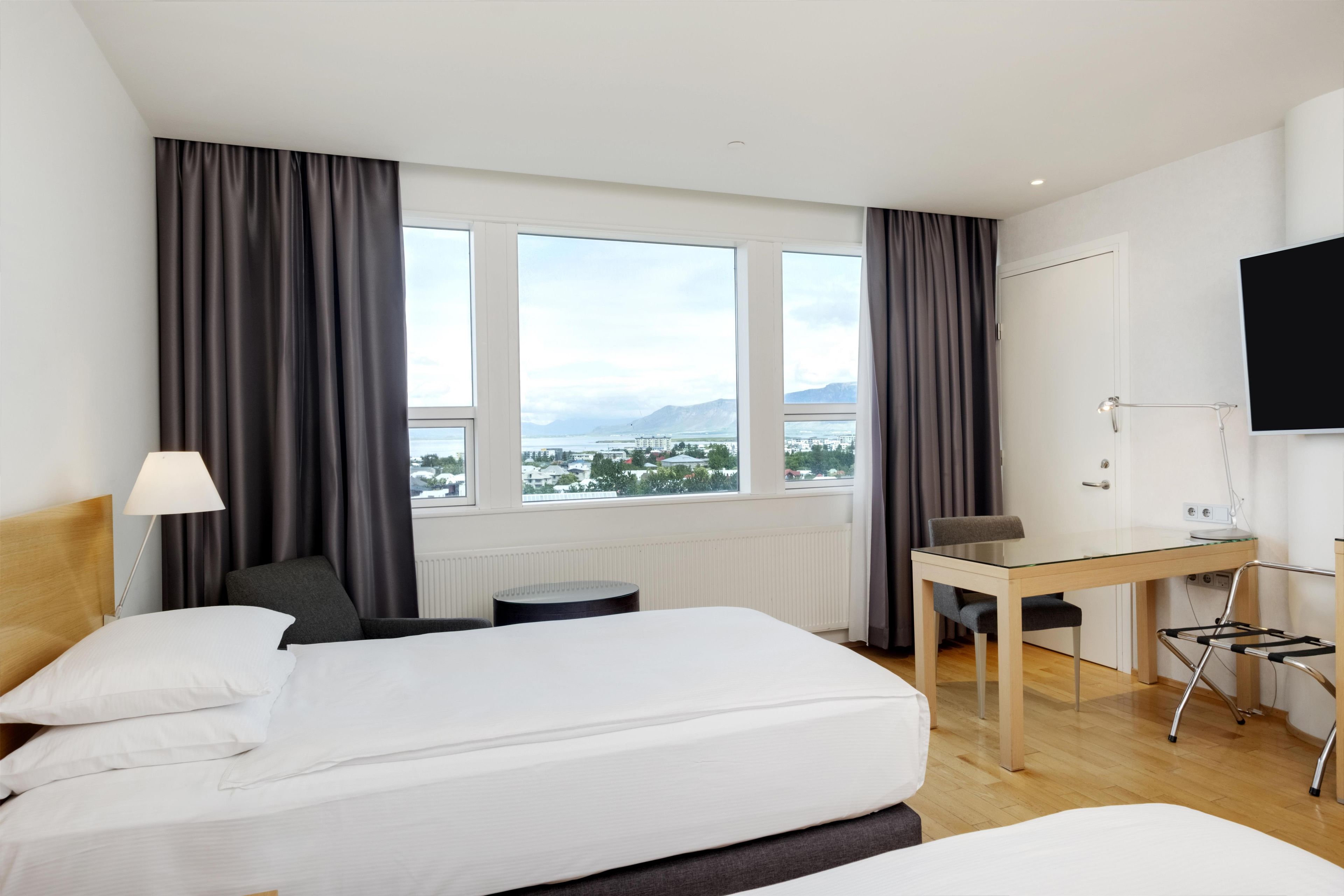 Ein Hotelzimmer mit Bett, Schreibtisch, Stuhl und Fernseher.