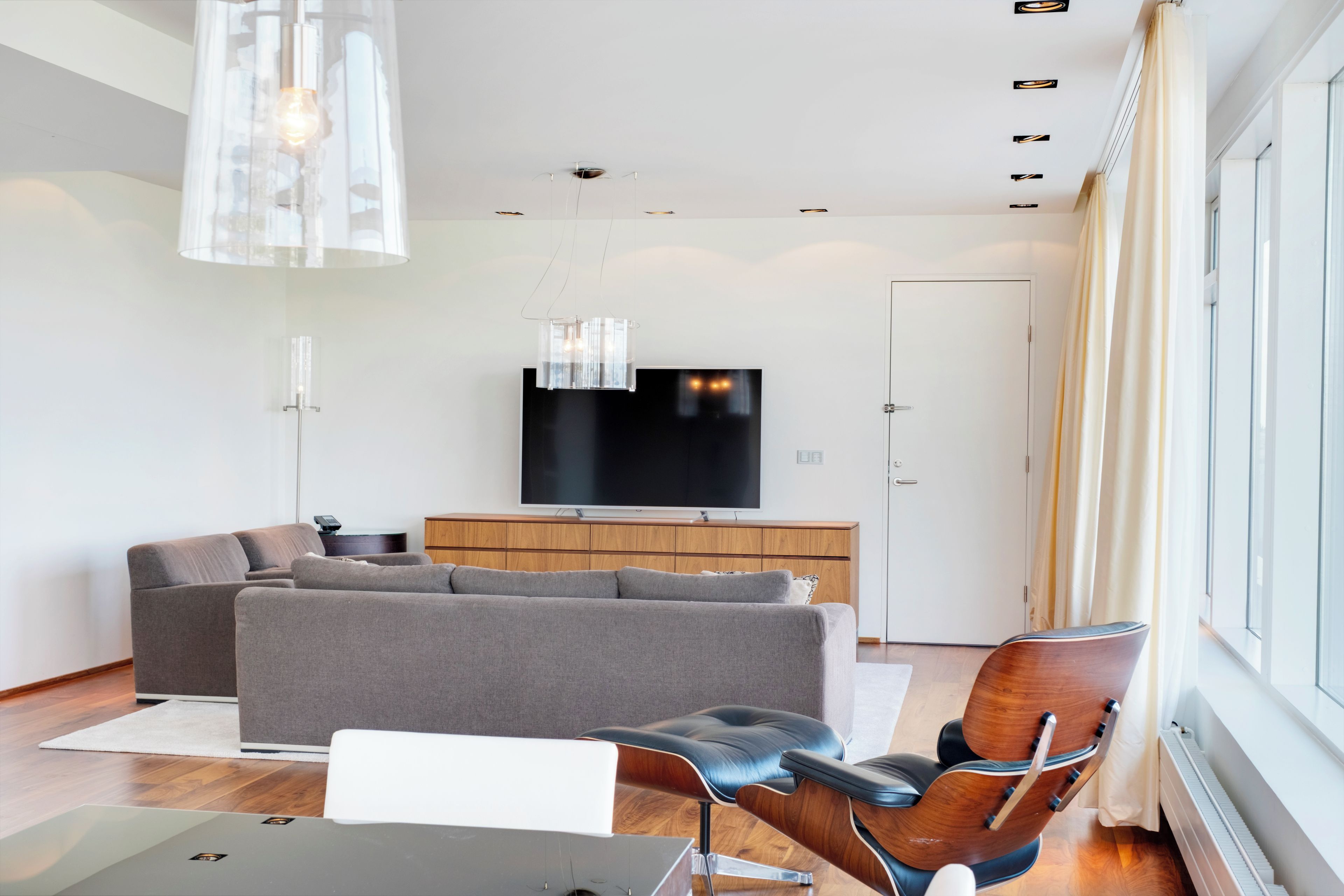 A modern living room with a sofa, a chair, a TV, and a wooden cabinet.