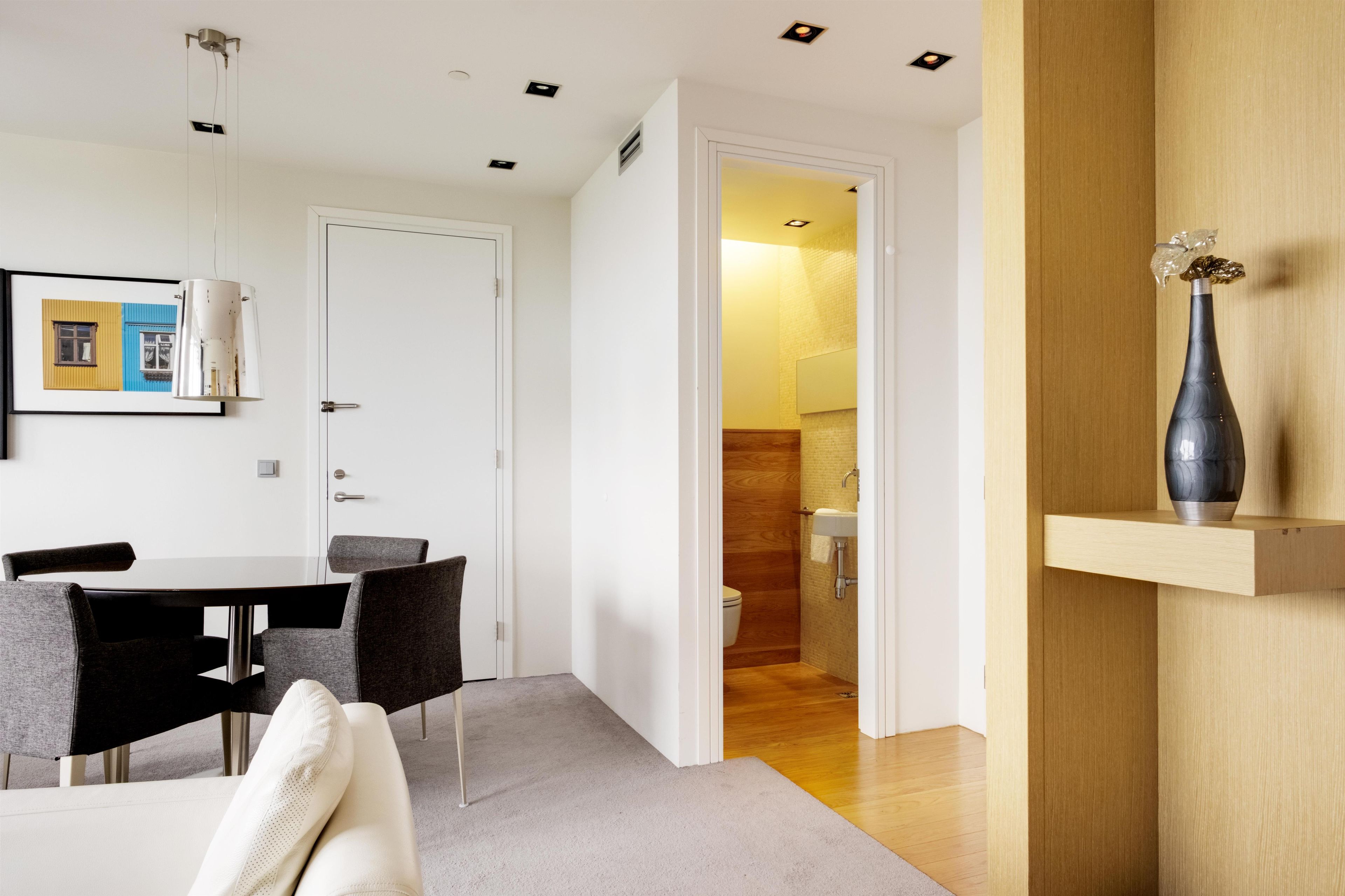 Um interior moderno com área de jantar, banheiro e corredor que leva a outro quarto.