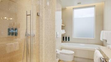 A modern bathroom with a glass-enclosed shower, a bathtub, and a toilet.