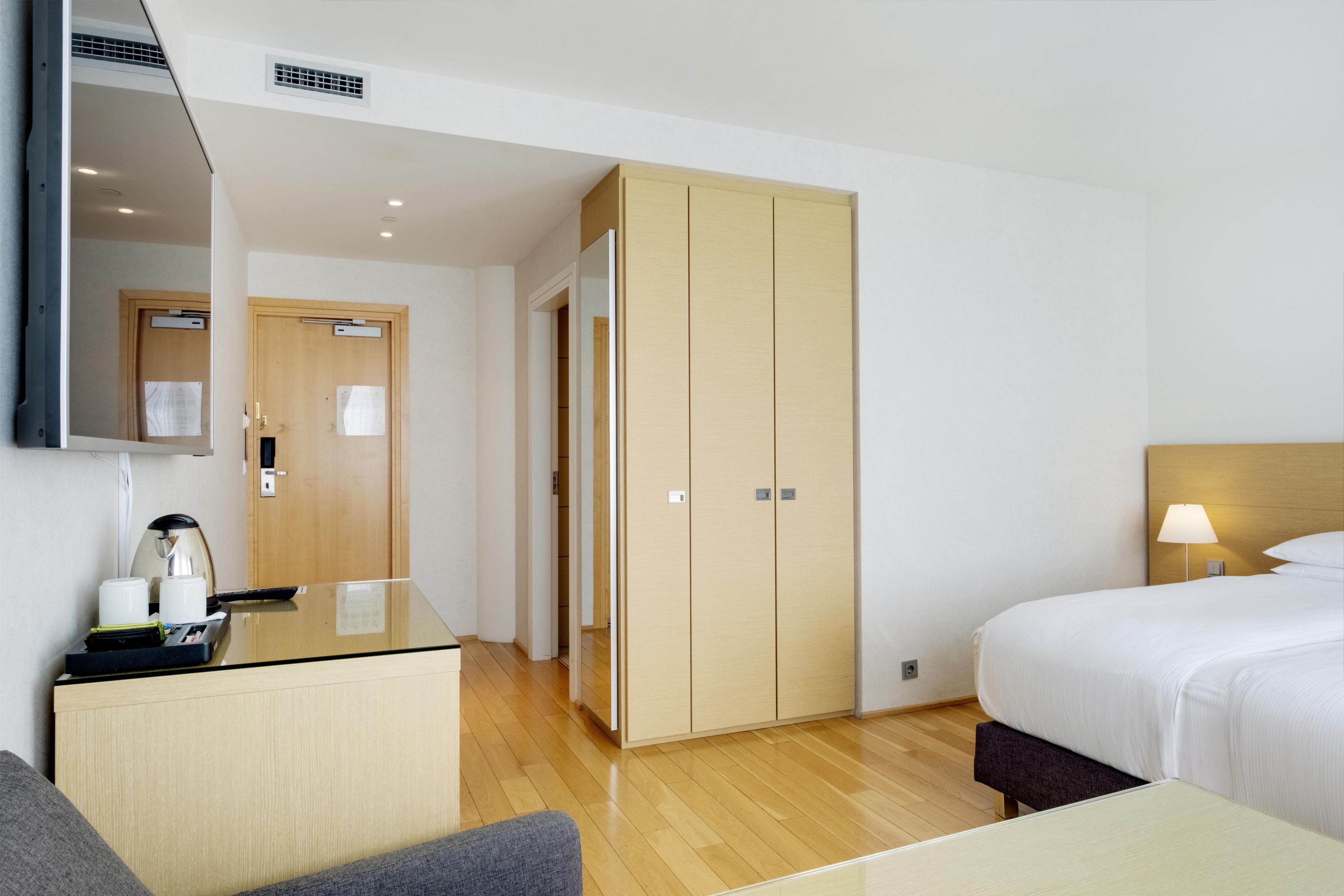 Habitación de hotel con cama, mesita de noche, lámpara y armario.