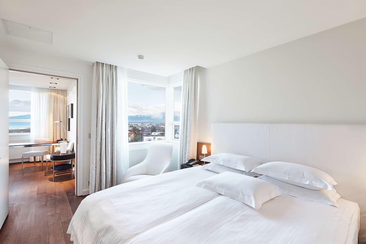 A hotel room with a large bed, a desk, and a view of the city.