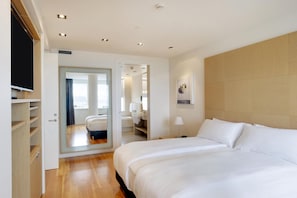 Habitación de hotel con cama, espejo, armario y baño visible a través de una puerta abierta.