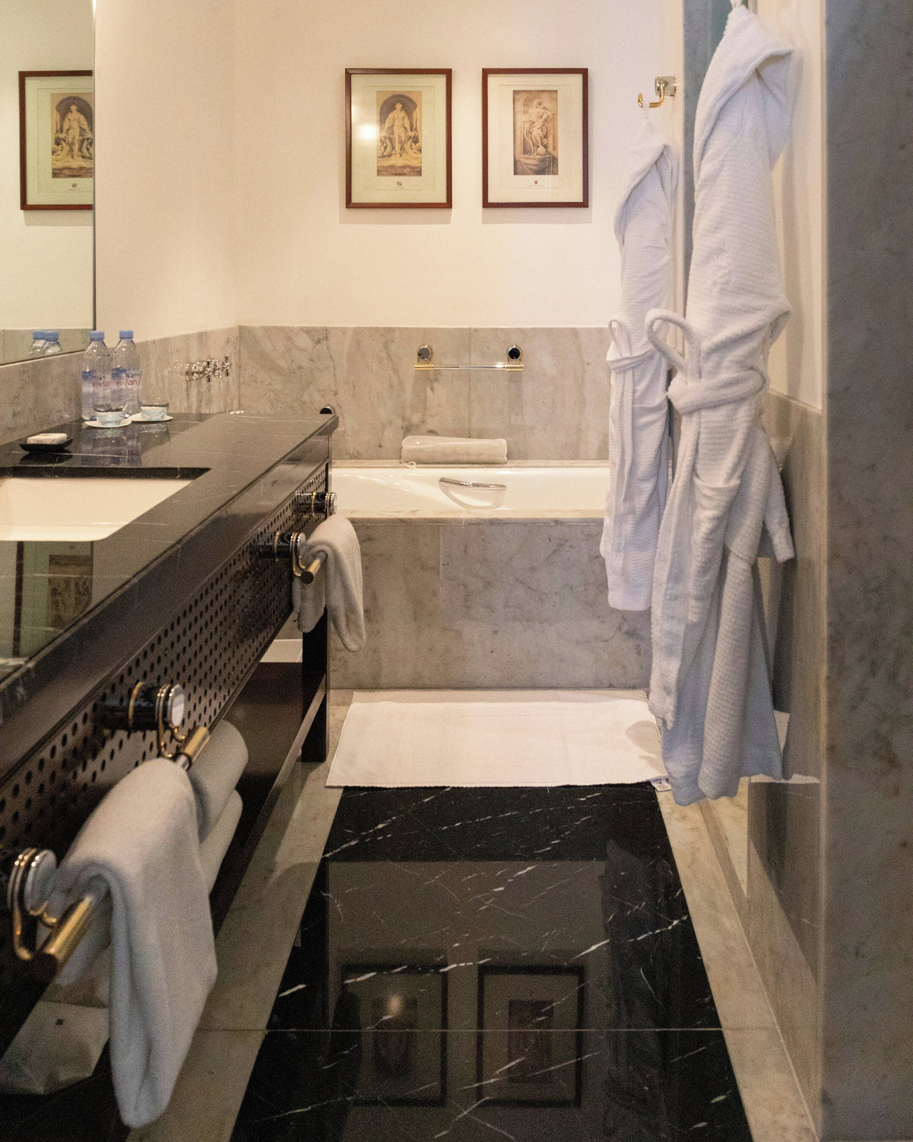 A bathroom with a sink, mirror, bathtub, and towels.