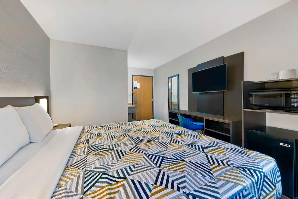 Ein Hotelzimmer mit einem großen Bett, einem Flachbildfernseher, einer Mikrowelle und einem kleinen Kühlschrank.