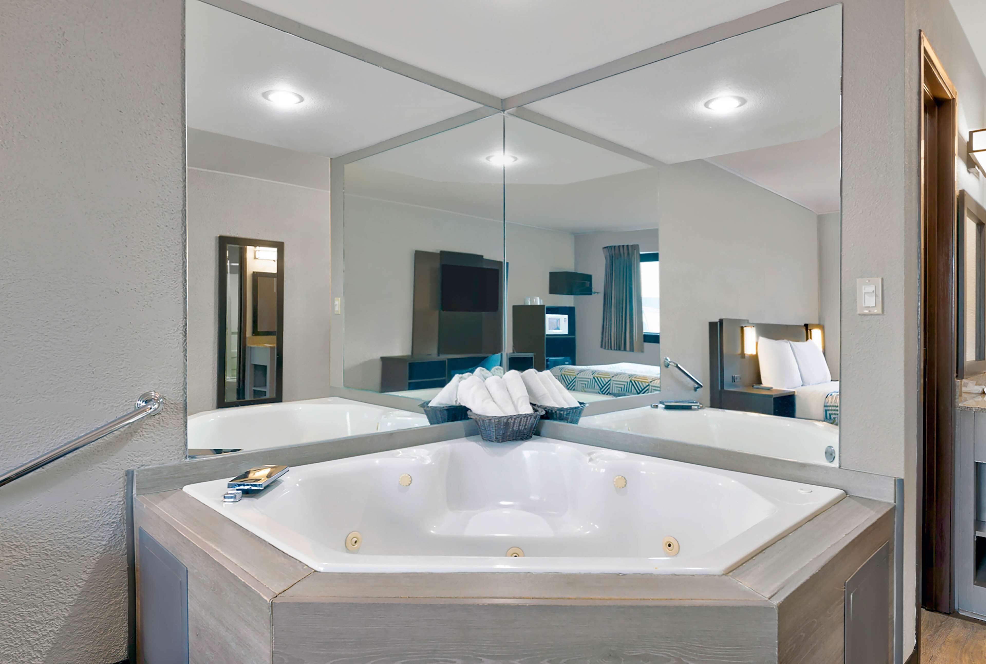 Een moderne badkamer met een groot bad, een spiegel en een houten wastafelmeubel.