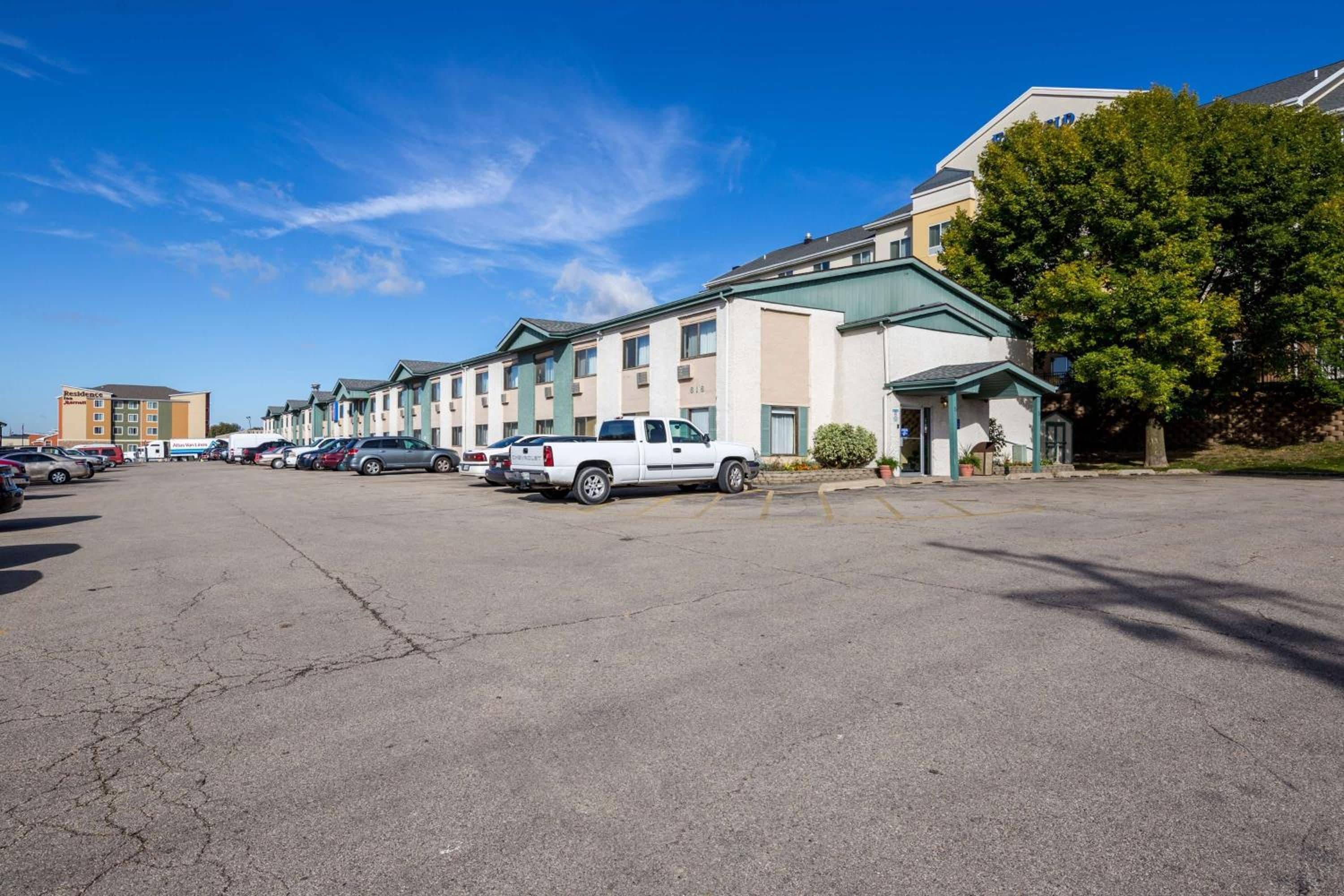 A parking lot with several cars and a building with a green roof.