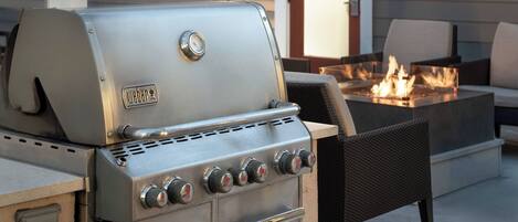 Una parrilla de gas Weber con cuatro quemadores, un quemador lateral y un termómetro integrado.