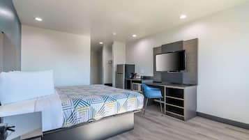 A modern hotel room with a bed, desk, chair, and a flat-screen TV.