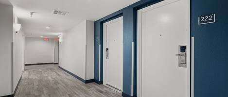 A hallway with a wooden floor, white doors, and a blue accent wall.