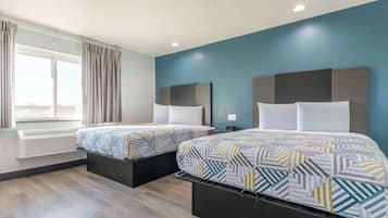 A modern hotel room with two beds, a large window with curtains, and a built-in air conditioning unit.