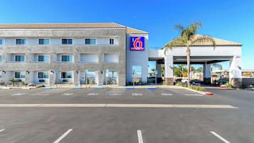 A 6th Street Suites hotel with a parking lot, multiple parking spaces, and a building facade with a blue sign.