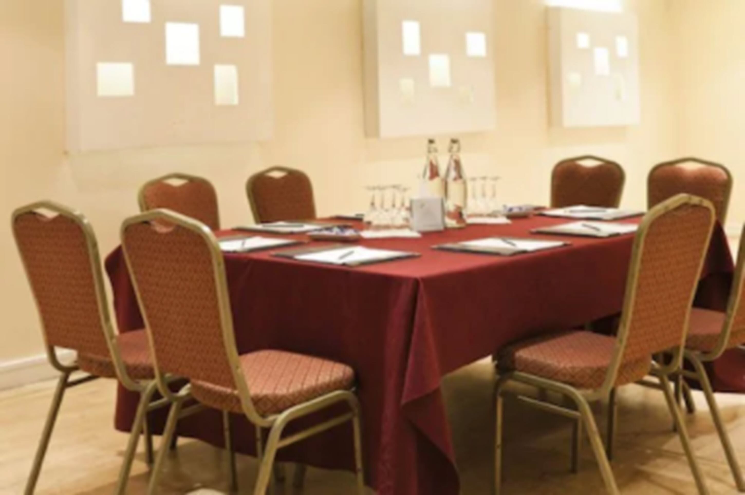 A conference room with a red table, eight chairs, and a whiteboard on the wall.