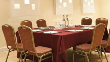 A conference room with a red table, eight chairs, and a whiteboard on the wall.